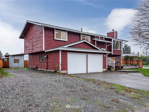 A three quarter view, emphasizing the RV/additional parking area along the side of the house and driveway.  The siding is cedar, which is strong and weather resistant.