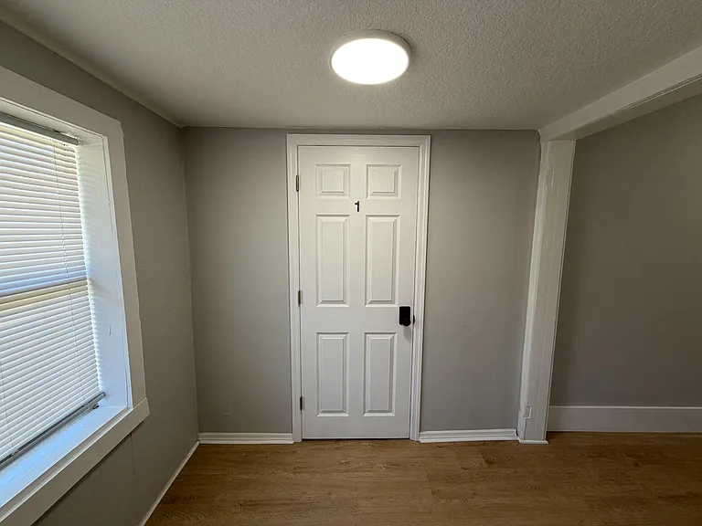 Compact interior entry/hall area with a window and overhead light, connecting to adjacent rooms with durable flooring.
