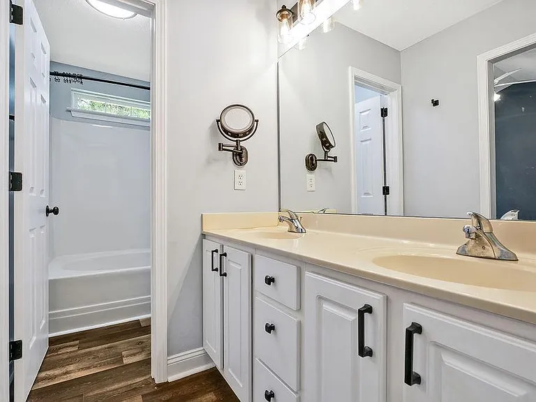 Split master bathroom. Dual sink with large vanity mirror, then door to the toilet and shower.