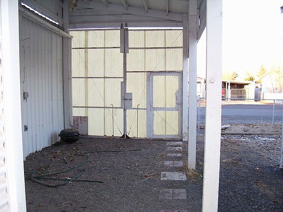 Large doors at end of tall covered area that can be used for RV Parking, boat or vehicle