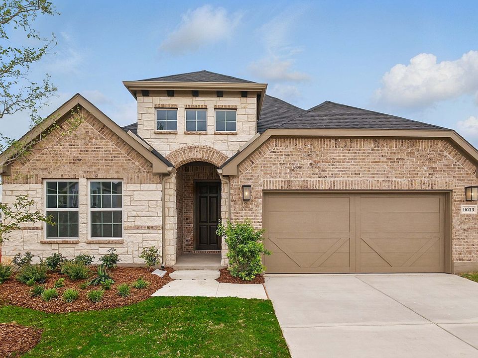 Elegant arched doorway, rich brick facade, two-car garage. Located in prestigious Juniper at Green M