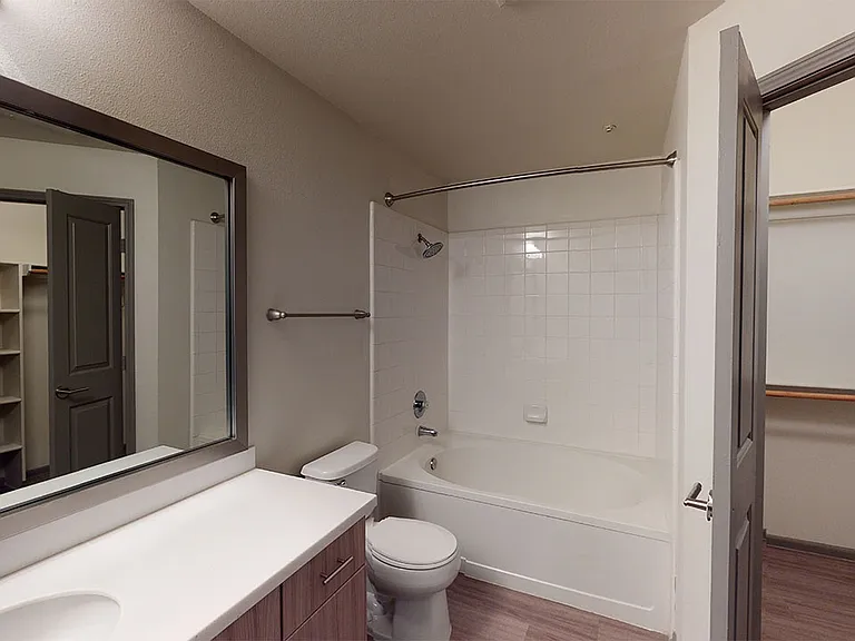 Apartment bathroom with wood-style flooring.
