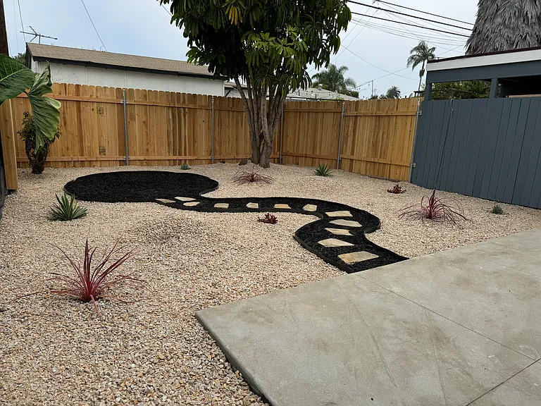 Fenced back yard with large patio and nicely laid out rock garden with succulents.