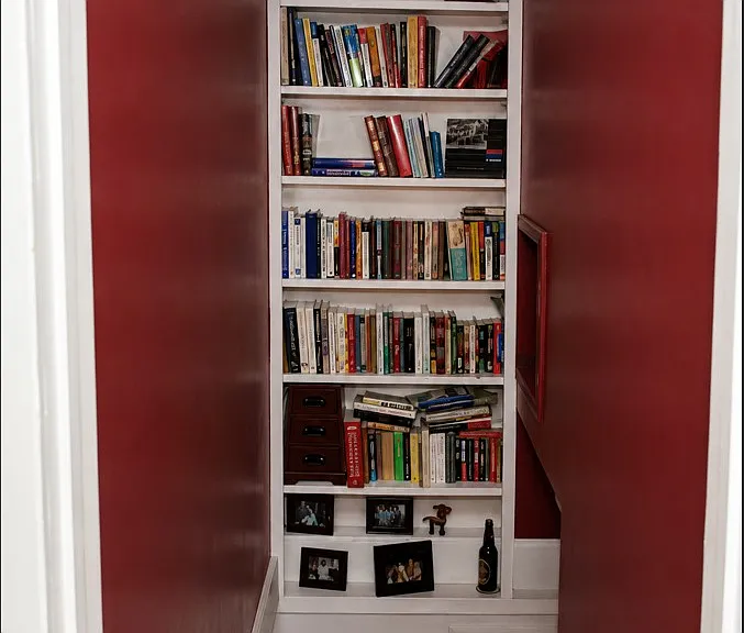 staircase with bookshelves leads to finished basement, office, and laundry room