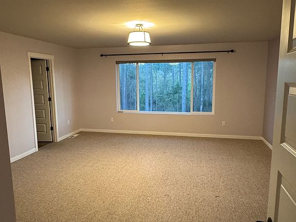 Large primary suite with huge window and a view of the natural space behind the home