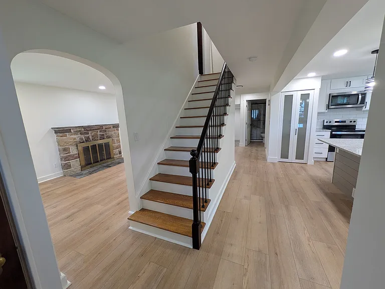 Stairs lead to 3 bedrooms and bathroom upstairs. Living room with fireplace on the left and kitchen on the right. Bathroom at the end of the hall.