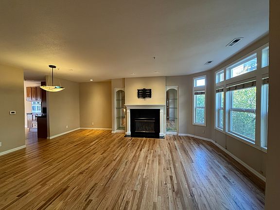 Living room with large window, fireplace, TV mount, and Murano glass light fixtures. Hardwood floors. Dimmable lighting.