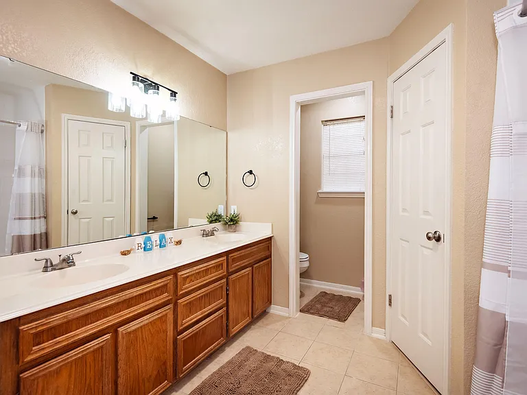 Spacious bathroom with double-sink vanity, large wall mirror, and ample cabinet storage for everyday essentials.