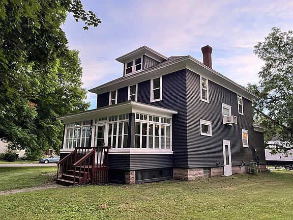 Exterior front with view of right side and side door that leads to basement.