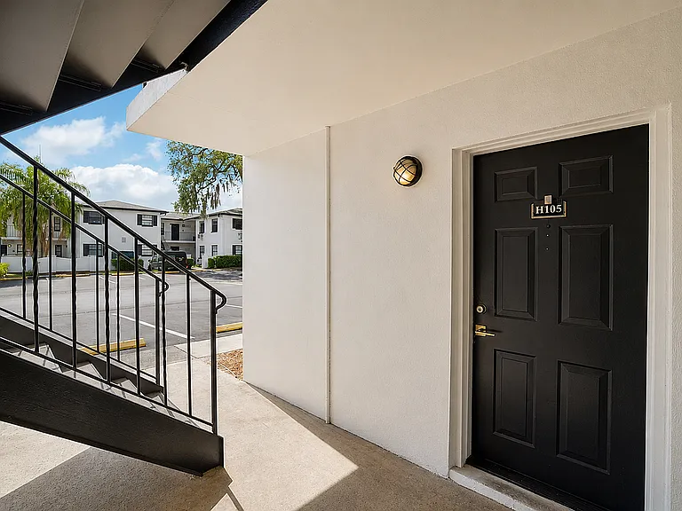 Inviting apartment entrance with modern black door and warm outdoor lighting, perfect for comfortable living.