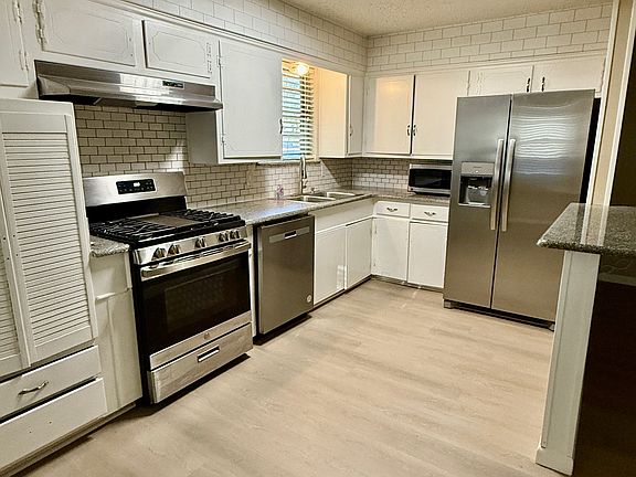 Kitchen with granite countertops, stainless steel appliances include gas range, dishwasher, brand new refrigerator & microwave.