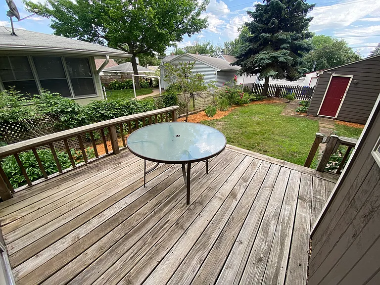 Back deck looking onto the private backyard with mature gardens. A lawnmower and yard tools are provided!