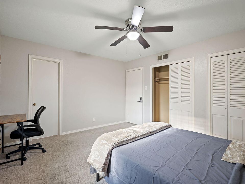 Spacious bedroom with ceiling fan, carpeted floors, and multiple closets including a large sliding-door wardrobe.