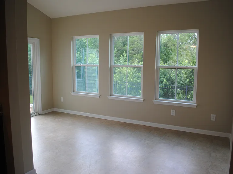 (prior to new laminate flooring) Large sunroom with tons of light. Great kids playroom. Sliding doors to back patio. Notice the green space! No neighbors behind!