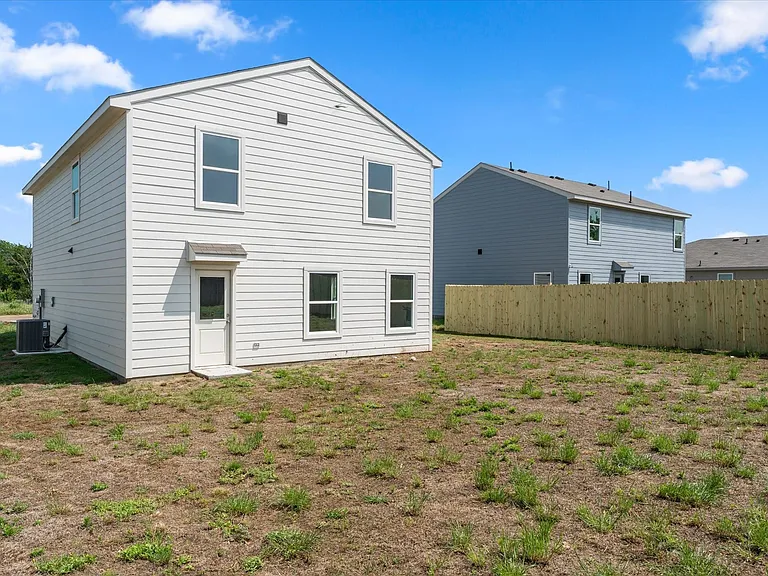 Rear exterior with white siding, multiple windows, and a back door with an awning