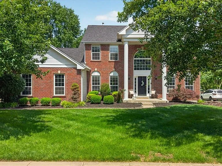 Traditional brick exterior featuring a prominent two-story entry with white columns and a grand arched window