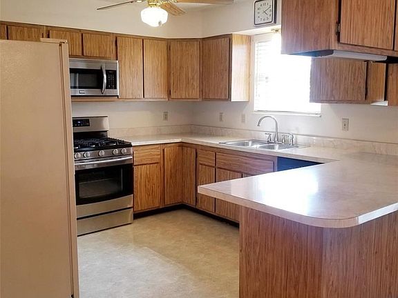 Kitchen with plenty of cabinet space, large counter top with overhang for stools. Newer gas stove/oven and microwave. Ceiling fa