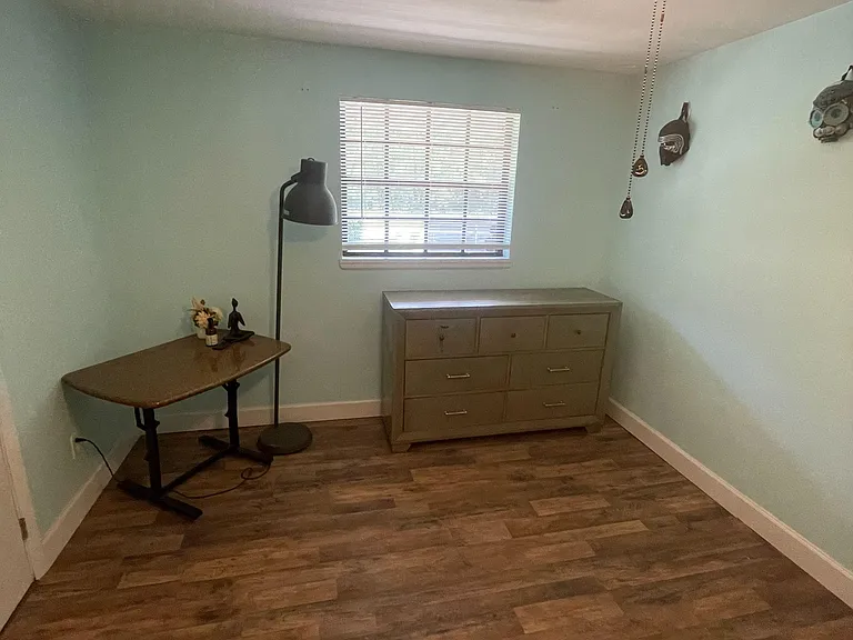 Room with wood-look flooring, a window with blinds, and a dresser for convenient in-room storage.