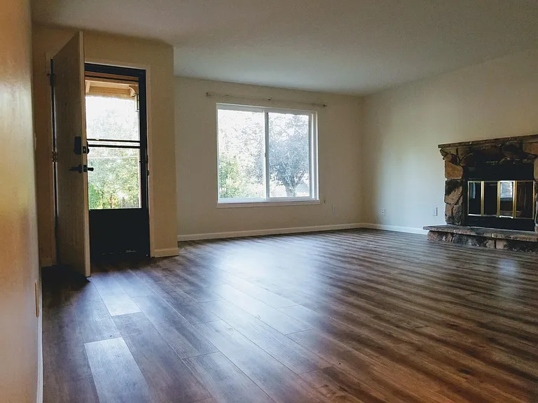 Spacious living room with wood burning fireplace is light and bright.