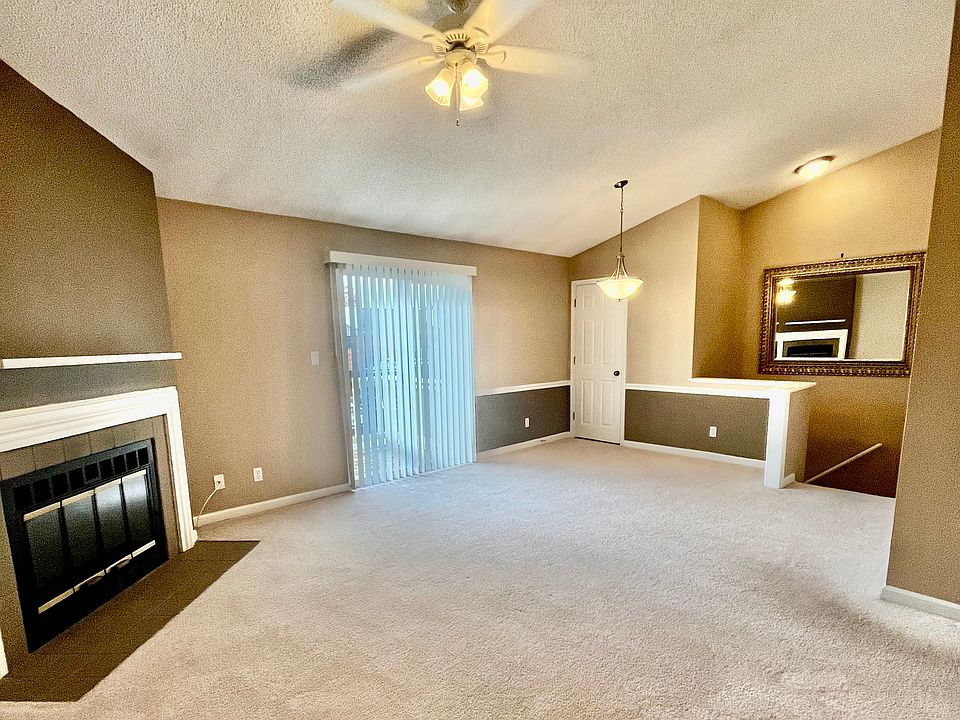 Living/dining room with fireplace, vaulted ceilings, and sliding glass doors that lead to front deck.