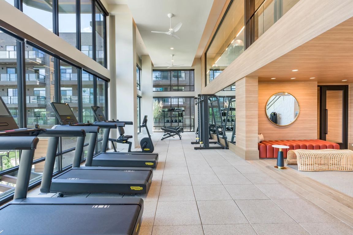 Light-filled fitness center with premium cardio and strength equipment plus relaxing lounge seating nearby.