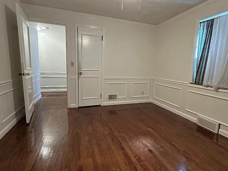 Bedroom 2 view 1 has a ceiling fan light, large window and hardwood flooring.