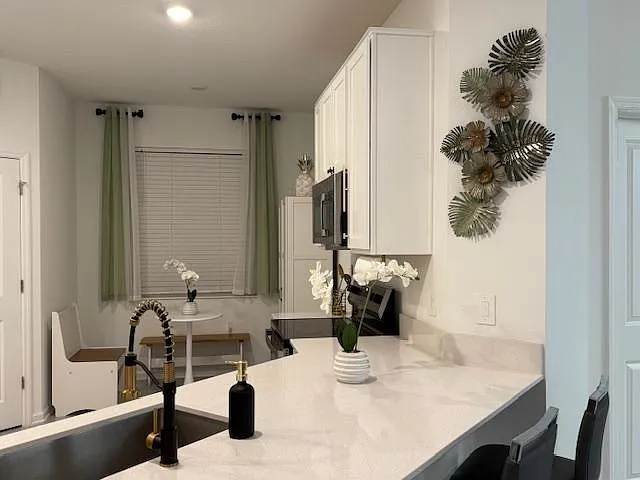 Open kitchen with white cabinetry, generous quartz-style counters, and a breakfast bar plus a small dining nook.