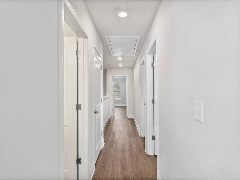 A bright hallway featuring warm wood flooring.