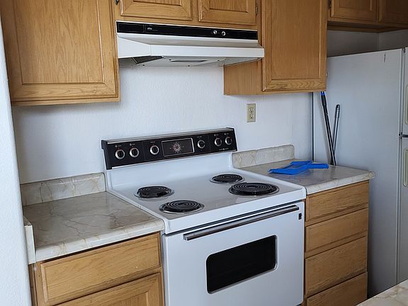 Electric range in kitchen with exhaust hood.