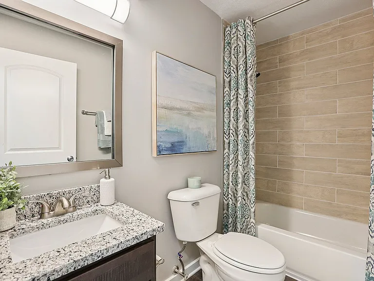 Bright bathroom with granite counters and bathtub