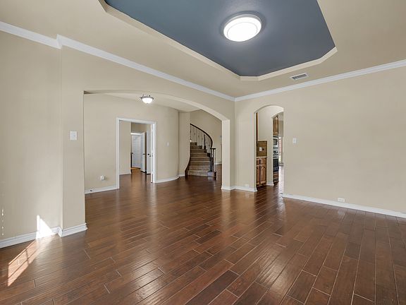 Spacious dining area with elegant hardwood flooring, offering a seamless flow towards the grand stairway leading to the second story. The open design connects effortlessly to the living room, creating a warm and inviting space for entertaining and family