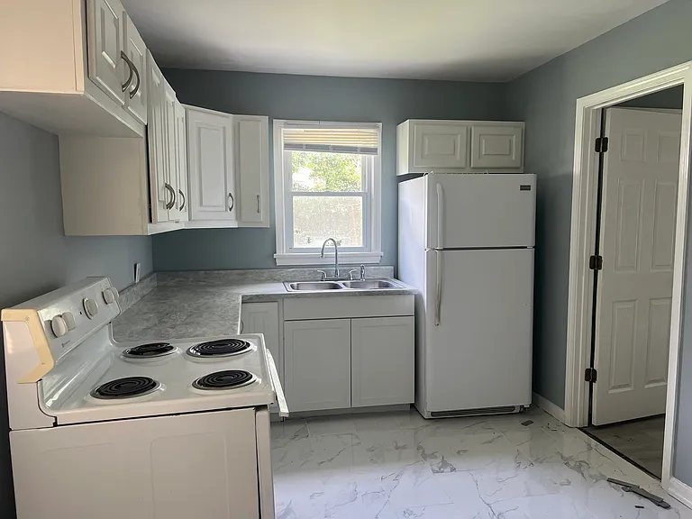 another view of kitchen with elctric stove and refrigerator and new countertop.