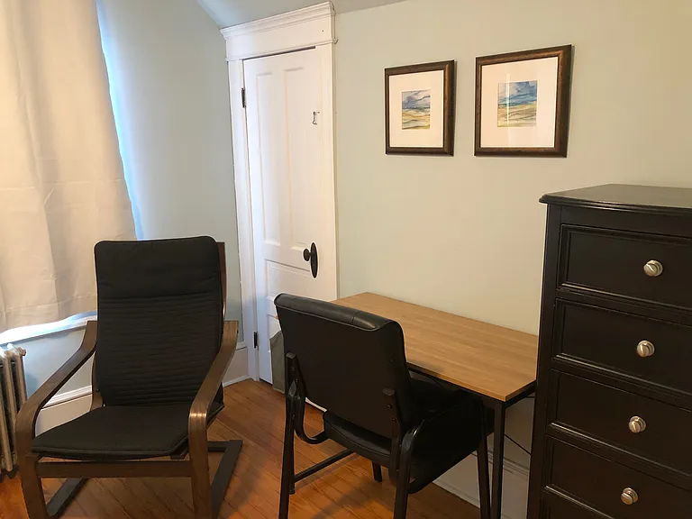 South-facing front bedroom has twin size bed, bedside table, small dresser, chair, ceiling fan & closet. This bedroom also has dedicated work space with desk and chair.