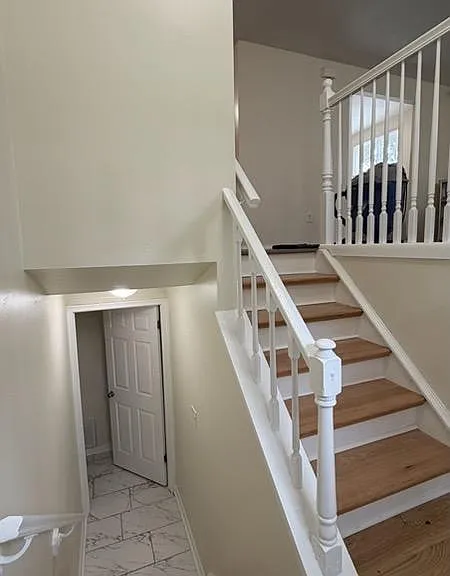 Split-level stairwell with hardwood steps, white railings, and an open landing connecting multiple floors.