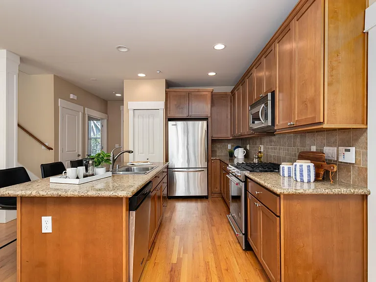 Kitchen with granite countertops, stainless steel appliances, gas stove, full-height backsplash, and large center island for informal gathering.