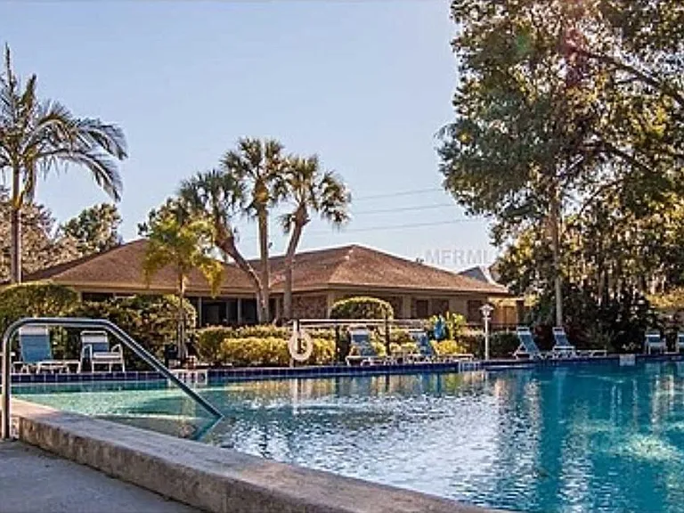 Lounge chairs and tables on patio surface surrounding pool.