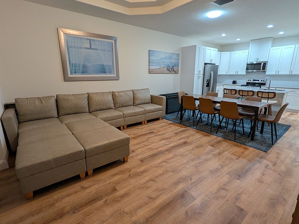 Open-concept living area with sectional sofa, dining space, kitchen island, and 55_ Samsung Smart TV.