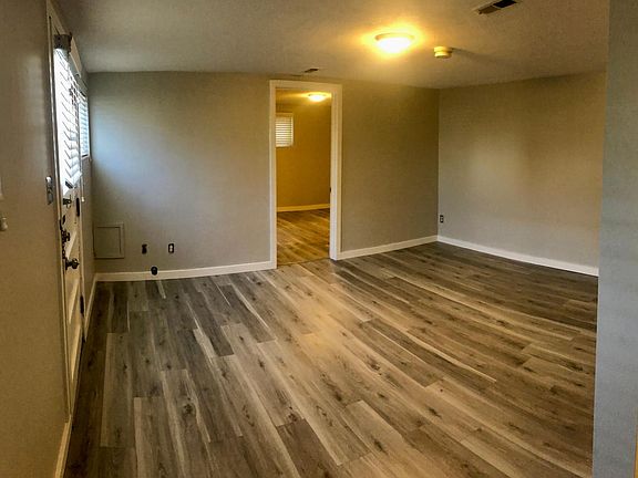 Luxury Vinyl flooring throughout entire unit. Living room looking into bedroom with kitchen off the the right.