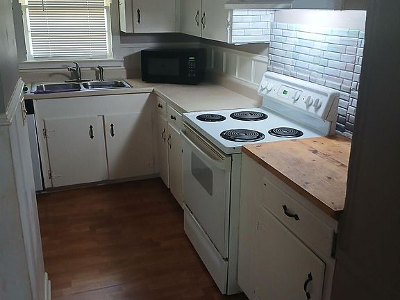 Large kitchen with electric stove, dishwasher, microwave and fridge.