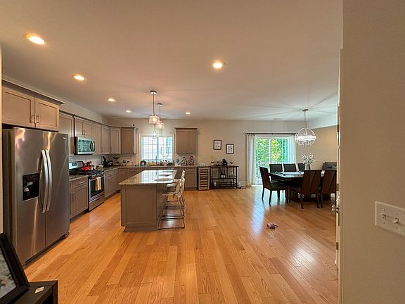 Main floor, kitchen with stainless steel appliances and granite countertops. Opens into dining room and family room, open concept floor plan. Hardwood floors and carpeting. Access to small deck.