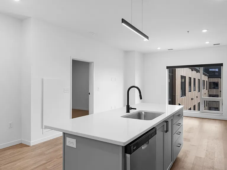 Modern apartment kitchen with sleek island, stylish faucet, bright wood floors, and large window offering ample natural light. Modern apartment kitchen with sleek island, stylish faucet, bright wood floors, and large window offering ample natural light.