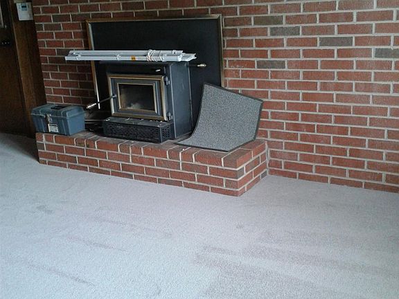 Family room showing fireplace with stove...marks in carpet are merely vacuum marks in the knap. Door to 2 car garage with doors with remotes is on the left
