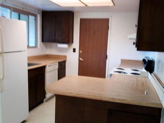 Kitchen with door to garage. Dining behind.