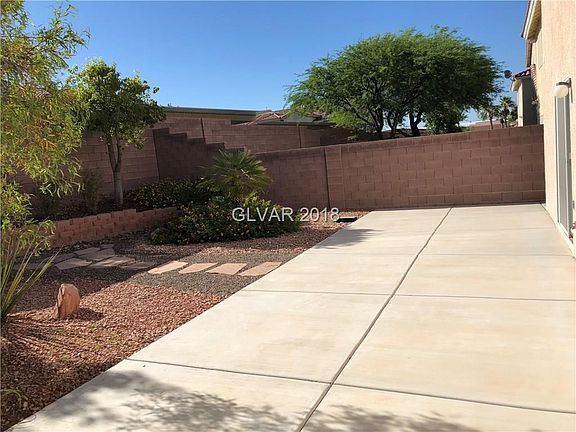 Backyard with mature landscaping and concrete play yard