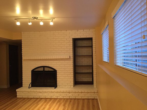 One end of the living room with painted brick fireplace, mantel, and built-in shelving.