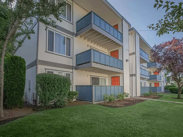 Exterior view of Foster Creek Apartments in Tukwila, with lush landscaping and bright building facade.