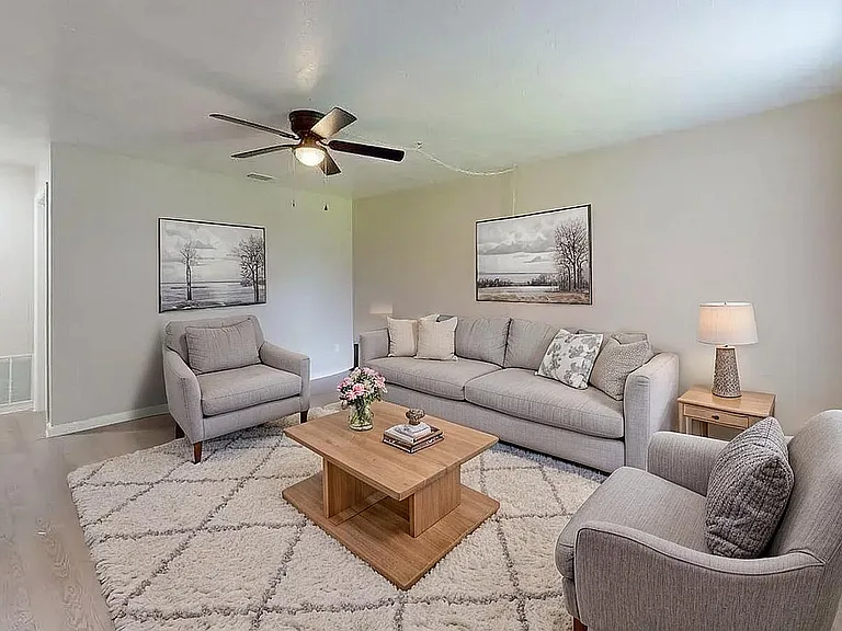 Inviting living room with elegant gray sofas, chic coffee table, and serene wall art, illuminated by natural light.