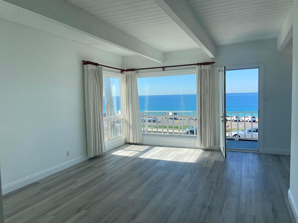 Huge ocean view open concept living room perfect for entertaining or relaxing with wood floors and beamed ceilings