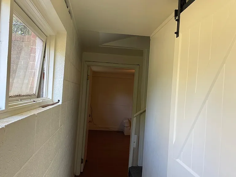 Looking down hallway with Bedroom door closed on right
Natural light from windows on left down hallway