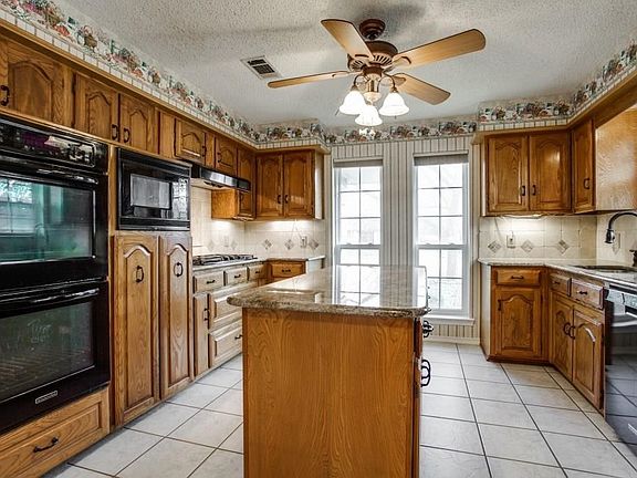 Imagine the baking and cooking you can do with this huge work island & double ovens! Five burner gas cooktop and built in microwave.  All black appliances, granite counters and more!